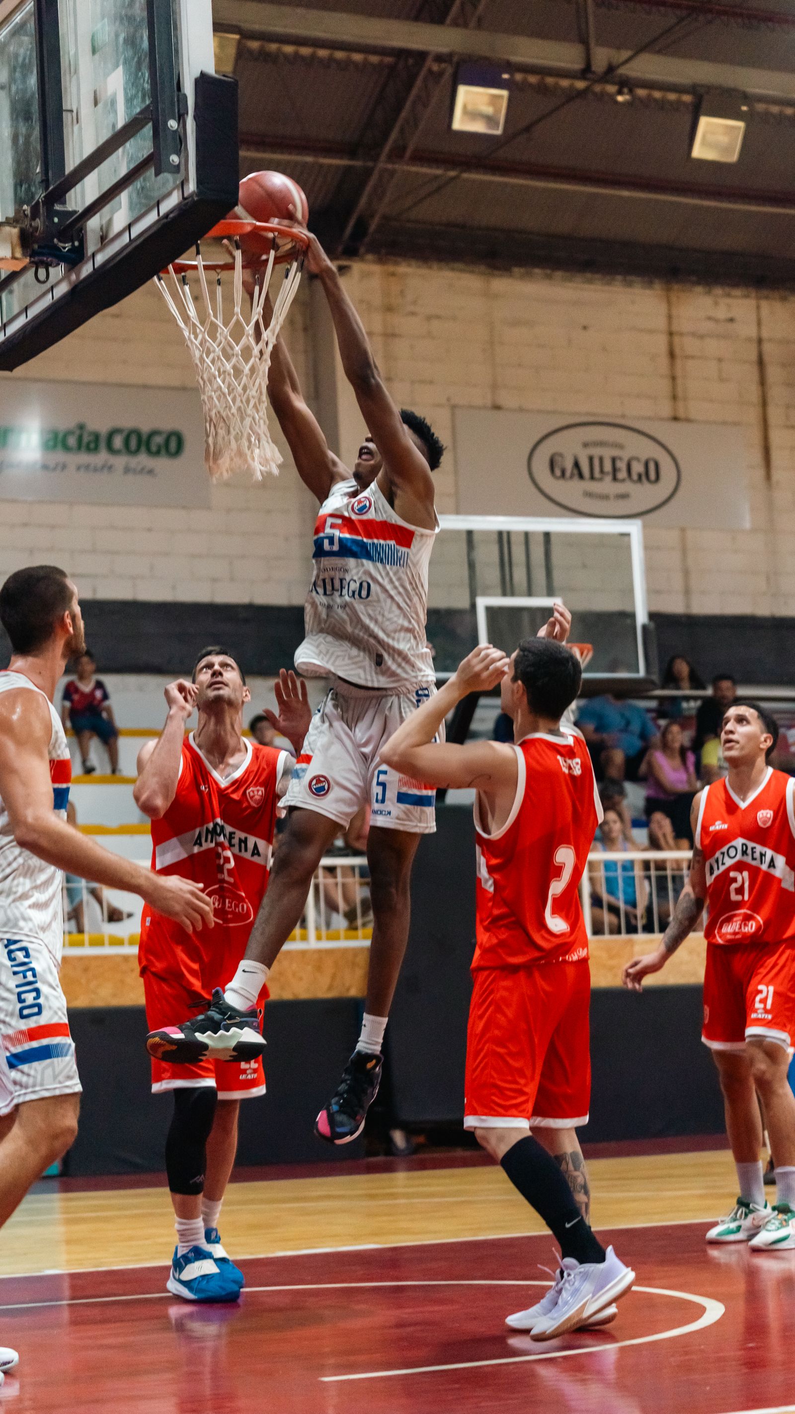 Basketball player performing a slam dunk during an energetic indoor game