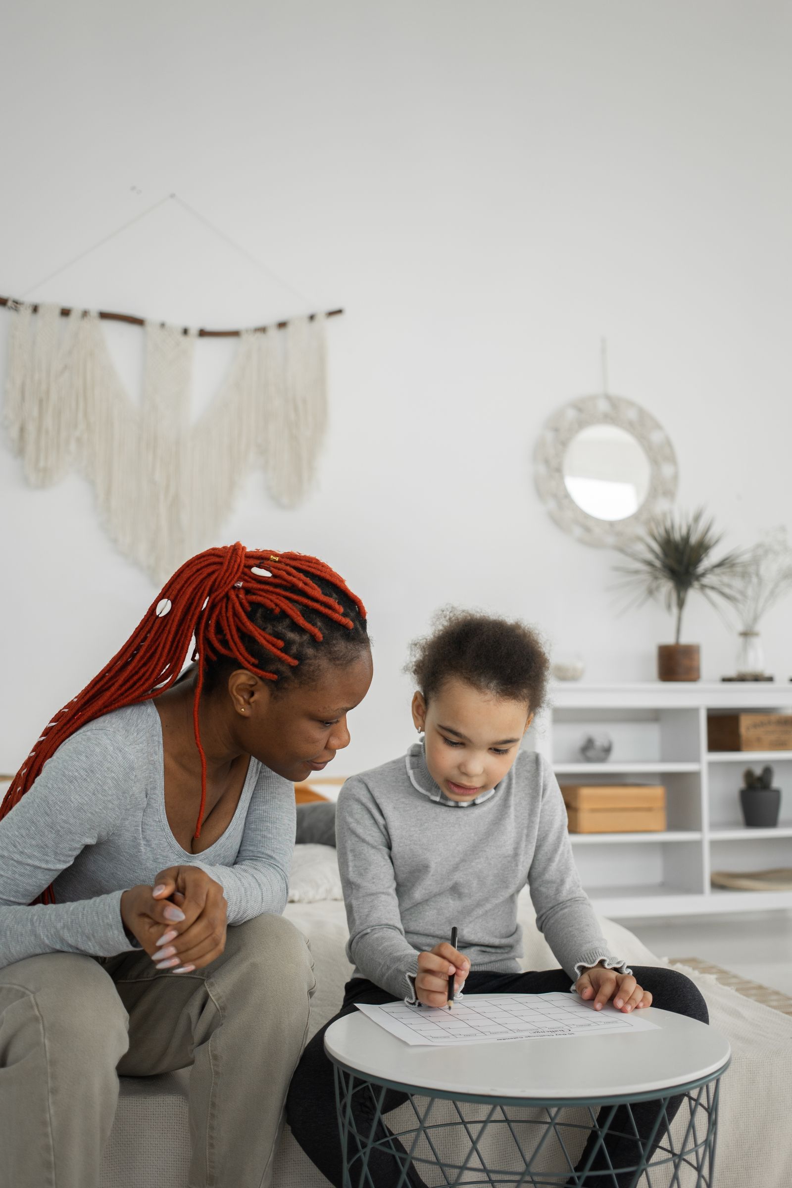 A mother attentively helping her daughter with schoolwork at home