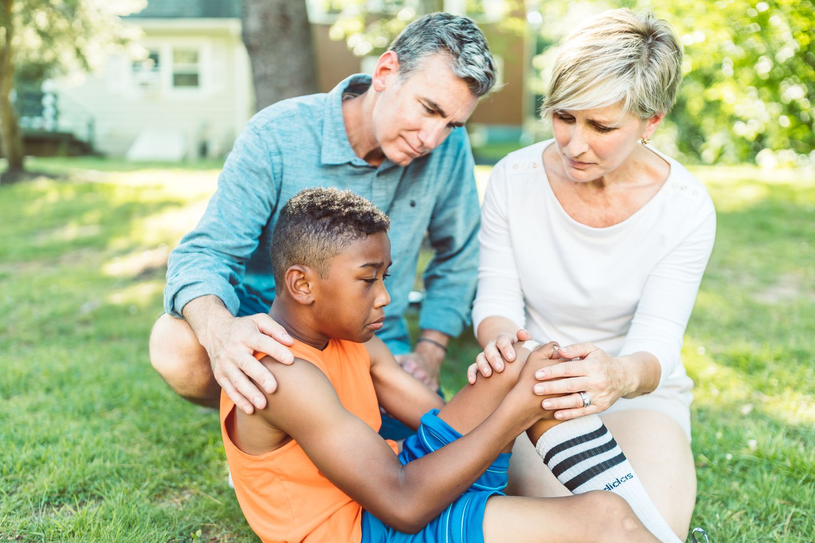 Parents comforting and caring for their son after a knee injury outdoors