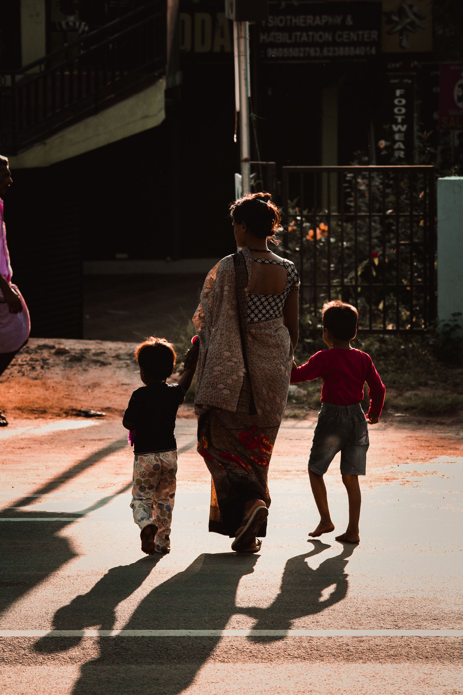 An adult walking two children safely across a street